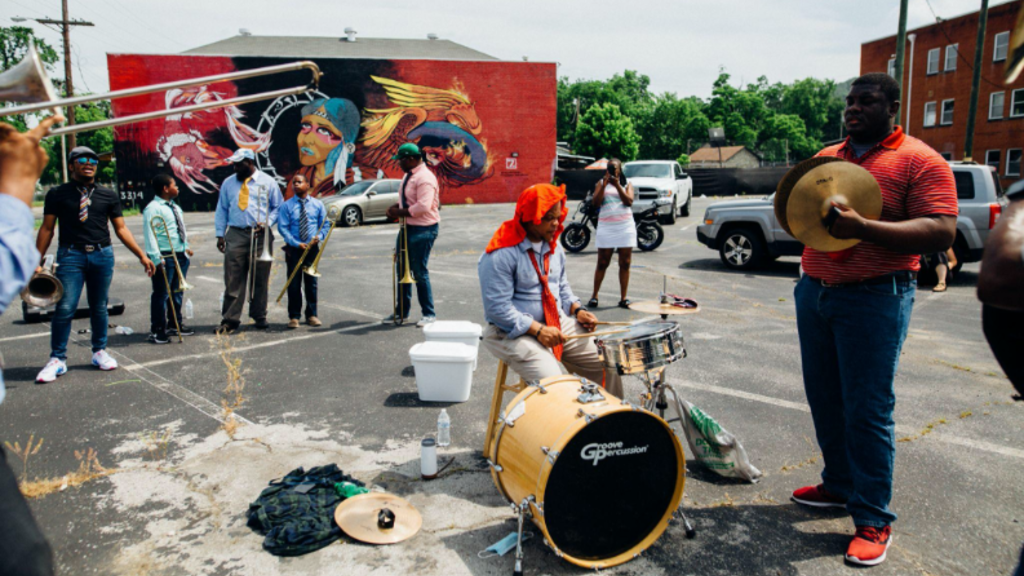 Band playing in street near large mural